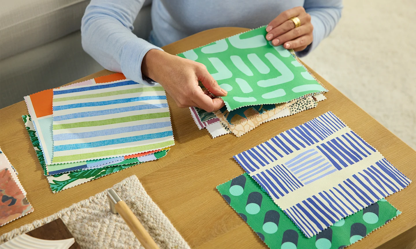 A person sorting through colorful blue and green Spoonflower fabric swatches