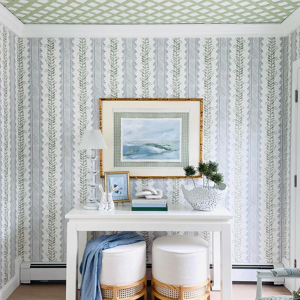 Preppy blue and green wallpaper and a coastal painting in a living space.