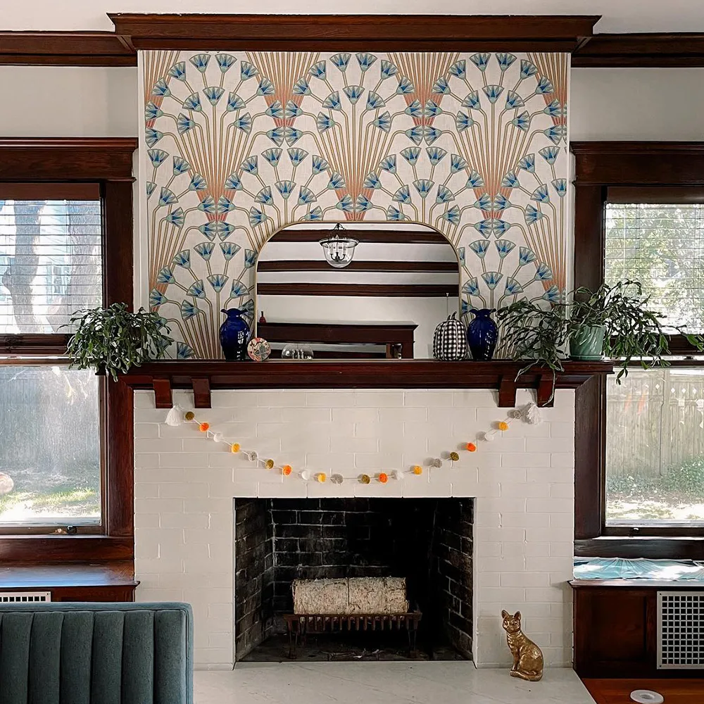 Fireplace mantle with art deco papyrus flowers wallpaper above it.