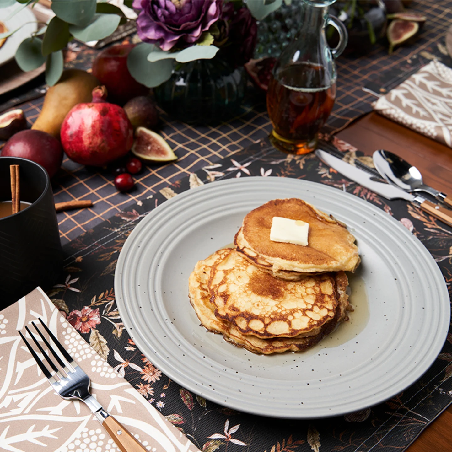 Dining table set with dark floral and pomegranate linens