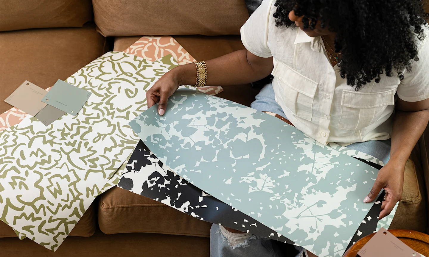 Marie holding swatches of her wallpaper designs from the INNER CALM capsule.