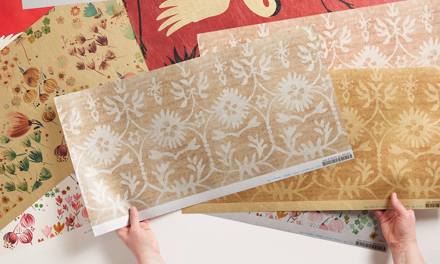 Hands holding metallic wallpaper swatches.