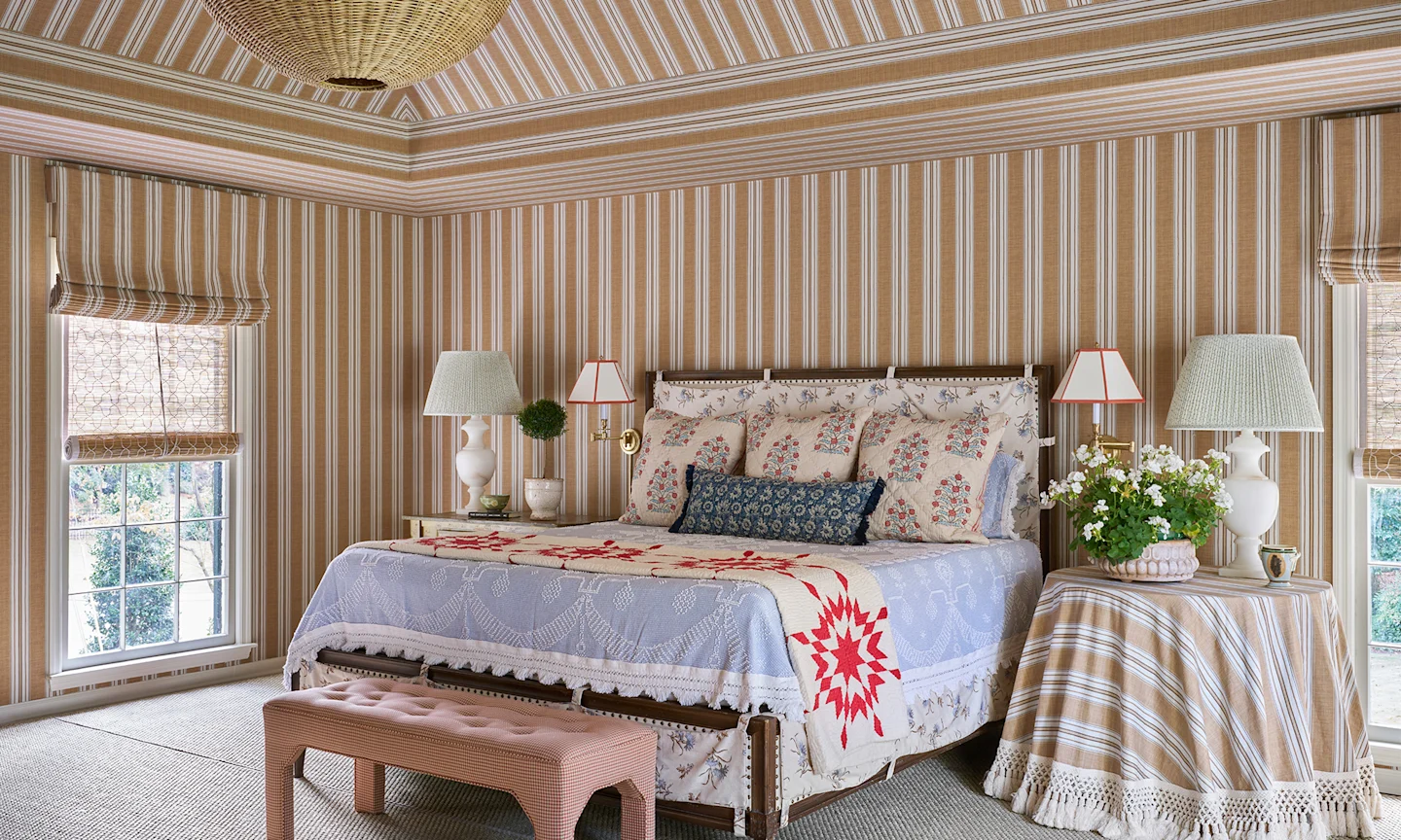 Bedroom wither striped walls and floral block print bedding.