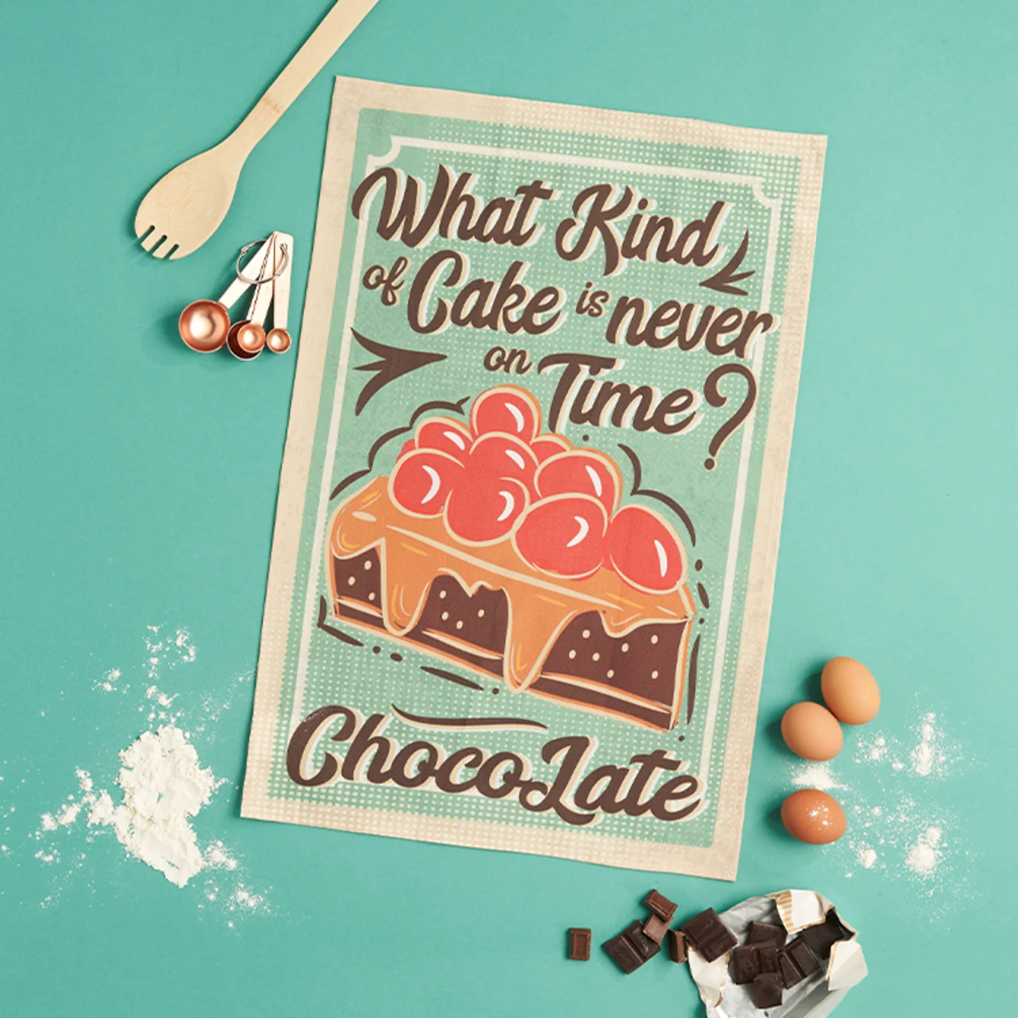 A whimsical cake pun tea towel on an aqua background